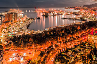 High angle view of illuminated city by buildings at night