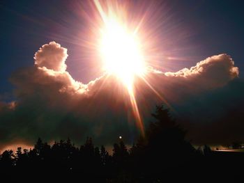 Low angle view of sunlight streaming through clouds