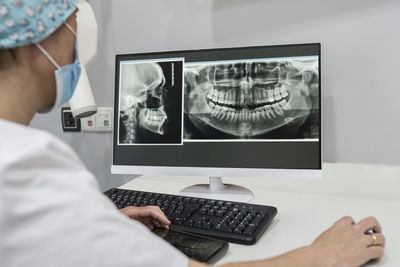 Dentist examining x-ray image on computer at medical clinic