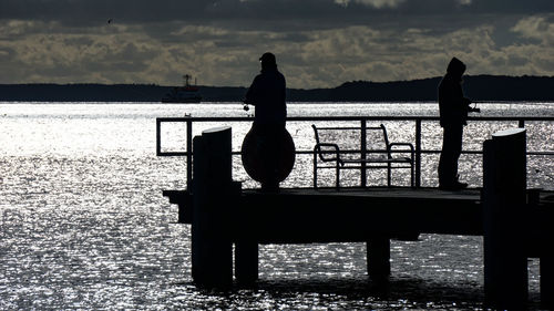 Silhouette people looking at sea against sky