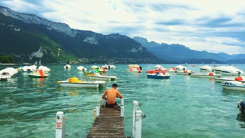 People on boats in sea against mountains