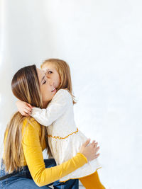 Mother embracing daughter against white background
