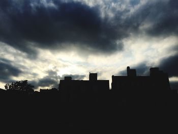 Silhouette built structures against cloudy sky