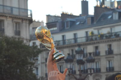 Person holding trophy against buildings in city