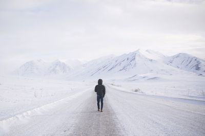 Rear view of man standing on snow covered mountain