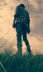 Low angle view of man standing on grassy field against sky during sunset