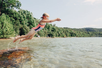 Full length of man jumping in water against sky