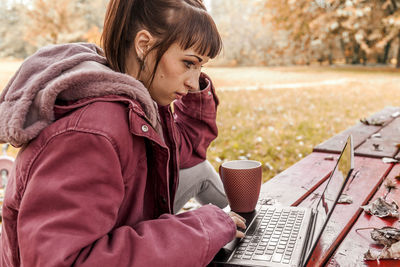 Rear view of woman using mobile phone in winter