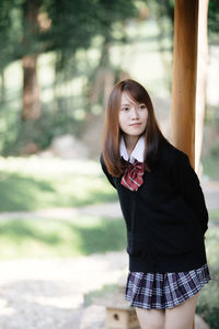 Young woman looking away while standing outdoors