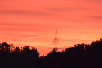 Silhouette of trees and tower against sky during sunset