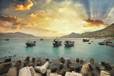 Boats moored on sea against sky during sunset