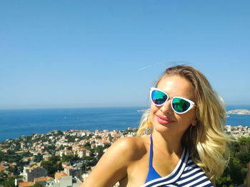 Portrait of young woman in sunglasses against blue sky