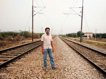 Portrait of a young man standing on railroad track