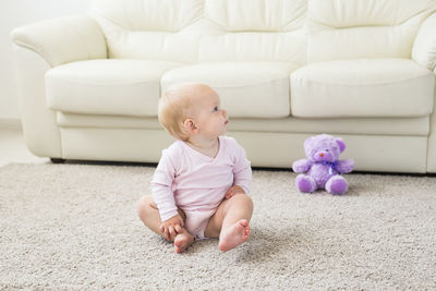 Cute baby girl sitting on sofa at home