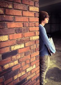 Man standing by brick wall in city