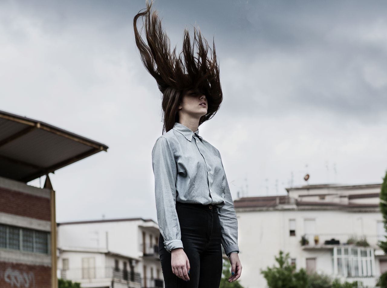 one person, sky, focus on foreground, architecture, standing, built structure, lifestyles, real people, casual clothing, leisure activity, building exterior, day, nature, three quarter length, city, women, cloud - sky, front view, hairstyle, outdoors