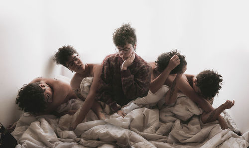 Multiple image of young woman sitting with blanket against wall