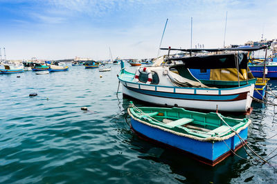 Boats moored at harbor against sky