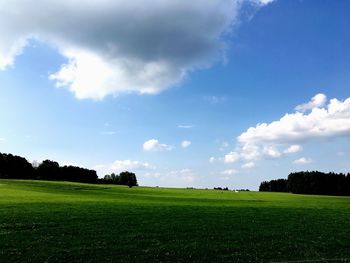 Scenic view of grassy field against cloudy sky