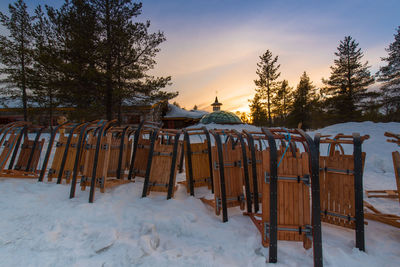 Wooden fence on snow covered field against sky