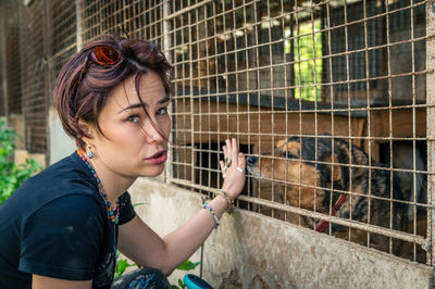 Dog at the shelter.  lonely dogs in cage with cheerful woman volunteer