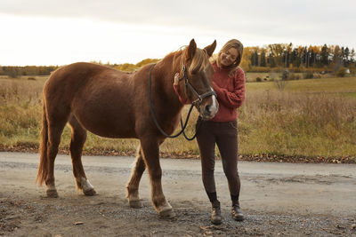 Woman stroking horse in farm