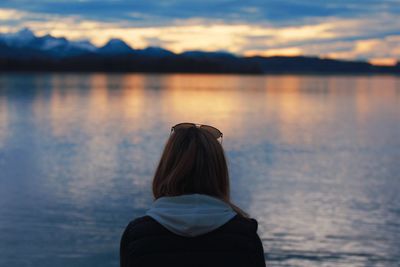 Rear view of woman against lake during sunset