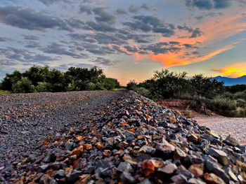 Surface level of pebbles against sky during sunset