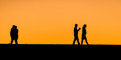 Silhouette people photographing against sunset sky