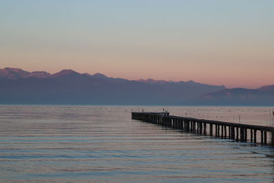 Pier over sea against sky during sunset