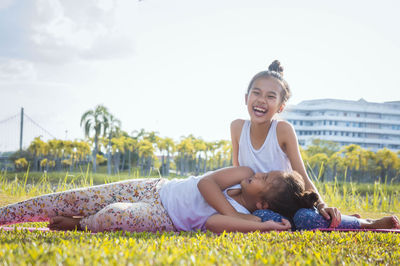 Full length of cheerful friends on grassy field against sky