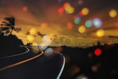 Cars on road against sky during sunset