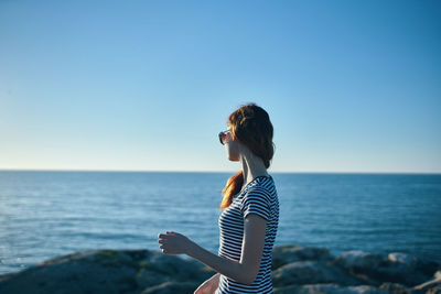 Side view of woman against sea against clear sky