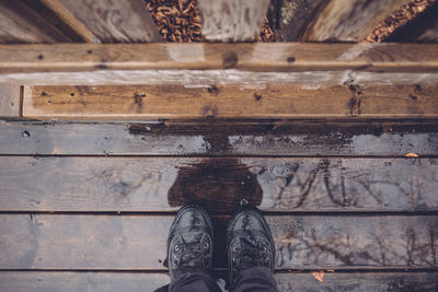 Low section of man standing on wet boardwalk