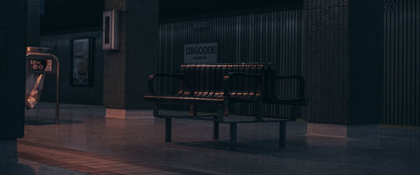 Empty chairs on sidewalk by building at night