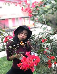 Beautiful young woman standing by pink flowering plants