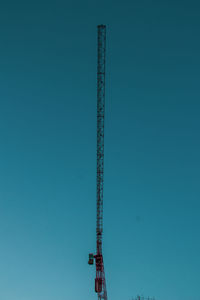 Low angle view of crane against clear blue sky