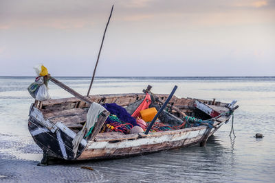 Fishing boats moored on sea against sky