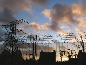 Low angle view of silhouette power lines against dramatic sky