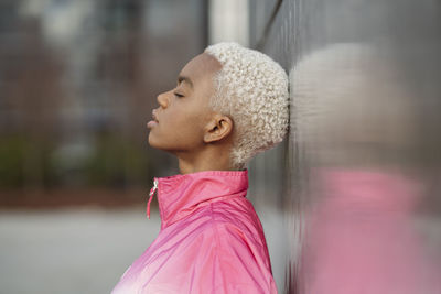 Woman with eyes closed leaning on wall