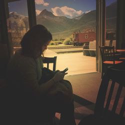 Side view of woman sitting at home