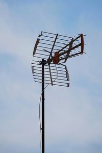 Low angle view of bird perching on pole against sky