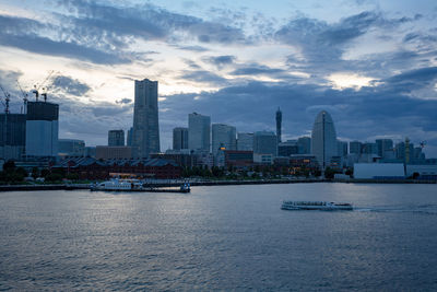 Sea by modern buildings against sky in city