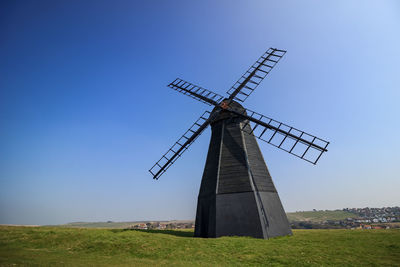 Traditional windmill on field against clear sky