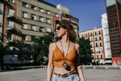 Young woman looking away while standing in city