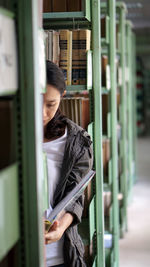 Woman standing amid bookshelf in library