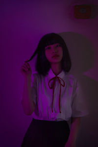 Portrait of young woman standing against wall