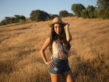 Portrait of young woman standing on field