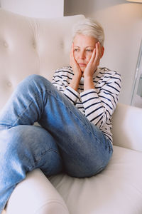 Portrait of young woman sitting on sofa at home