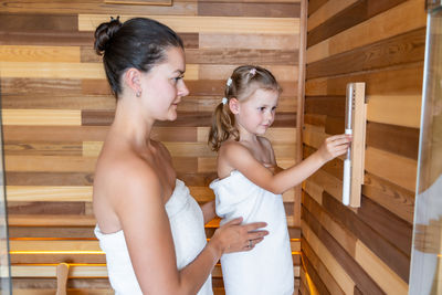 Side view of sisters sitting on wooden wall